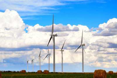 Windmills on field against sky