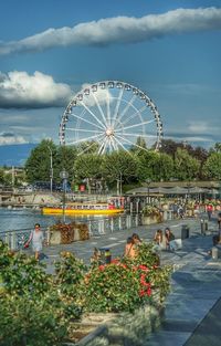 People at amusement park against sky