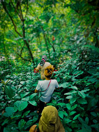 Midsection of woman with yellow leaves in forest