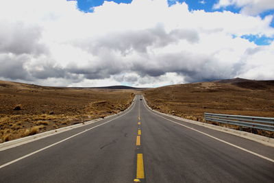 Empty road amidst landscape against sky