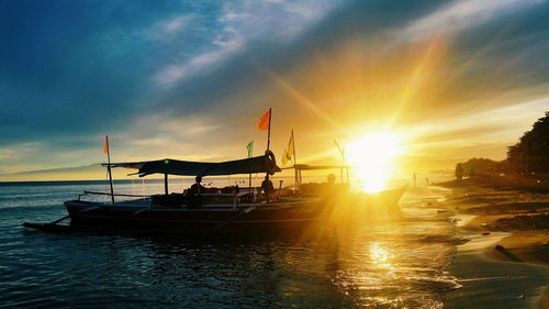 Silhouette boats moored on sea against sky during sunset