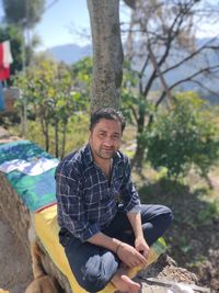 Portrait of man sitting on retaining wall