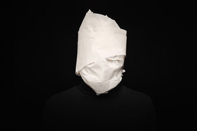 Close-up of person wearing mask against black background