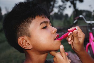 Close-up of boy applying lipstick