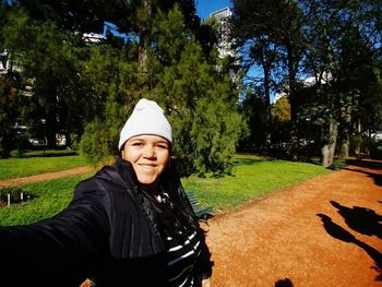 Portrait of smiling young woman against trees