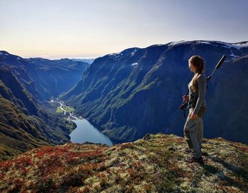 Rear view of female hunter looking at mountains against sky