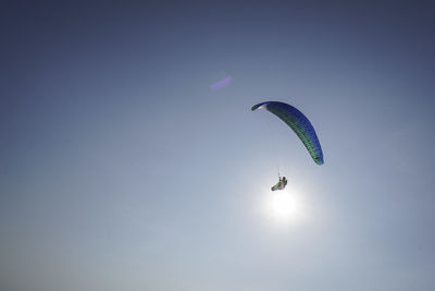 Low angle view of person paragliding against sky