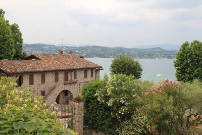 Built structure by trees and plants against sky on the lake
