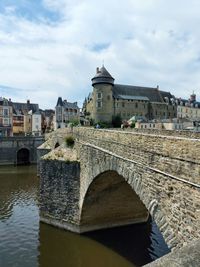 Arch bridge over river against buildings in city