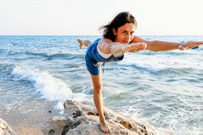 Portrait of woman standing at beach against sky