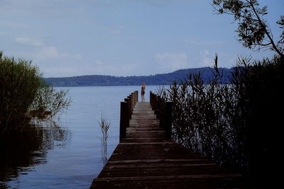 Wooden pier over lake against sky