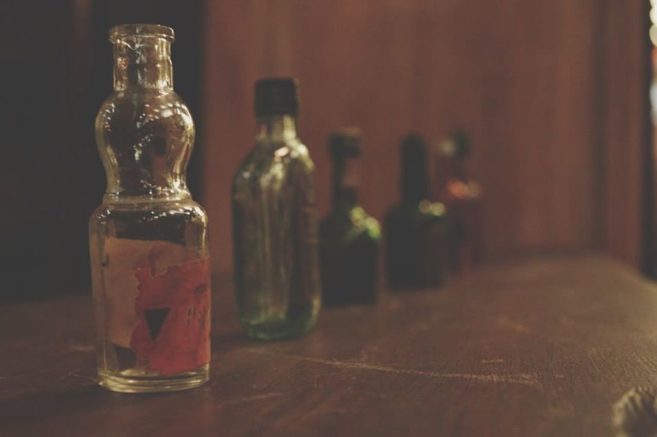 indoors, table, close-up, selective focus, still life, home interior, focus on foreground, wood - material, old-fashioned, music, no people, arts culture and entertainment, musical instrument, technology, part of, red, retro styled, bottle, reflection