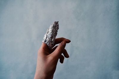 Close-up of finger wrapped in foil against sky
