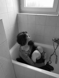 High angle view of woman sitting in bathroom