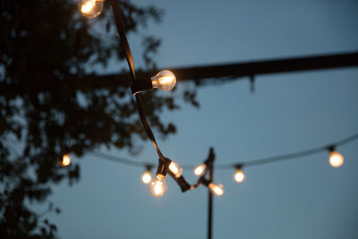 Low angle view of illuminated string light against sky at night