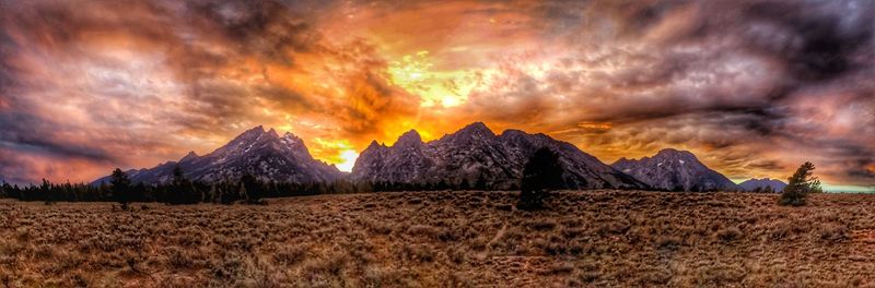 Scenic view of dramatic sky over land during sunset