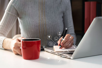 Midsection of man holding coffee cup on table