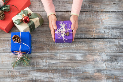 High angle view of woman holding christmas gift on wooden table