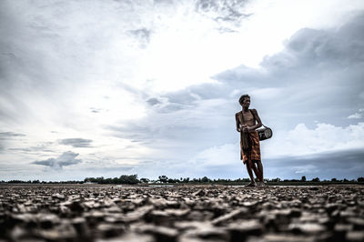 Low angle view of man standing on arid land against sky