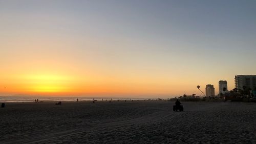 Silhouette people on beach against sky during sunset