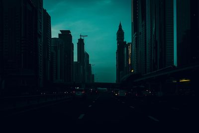 City street amidst buildings against sky at dusk