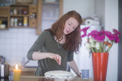 Young woman making birthday cake at home