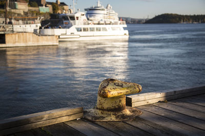 Rusty bollard on pier against ship moored on se