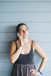 Portrait of smiling young woman standing against wall