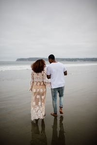 Mixed race couple walking along beach