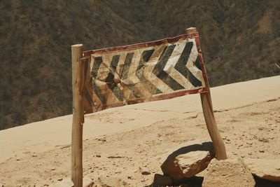 Crumpled warning sign at cliff edge on dusty road