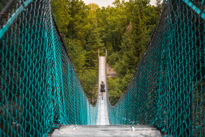Rear view of woman walking on pinawa suspension bridge
