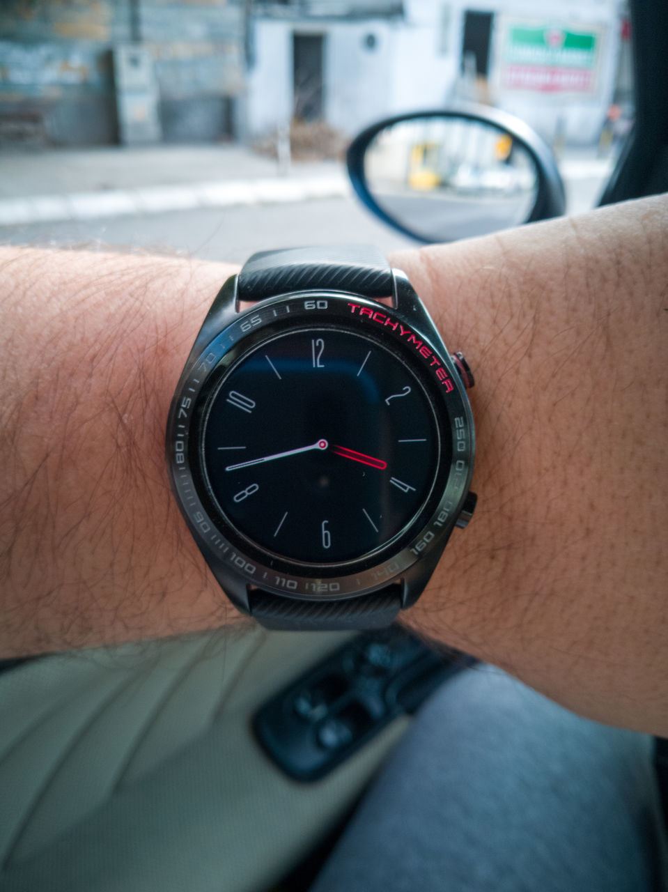 CLOSE-UP OF HAND HOLDING CLOCK AGAINST BLURRED WALL