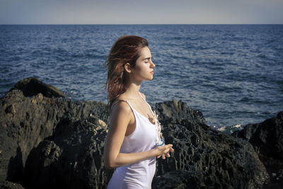 Young woman looking at sea against sky