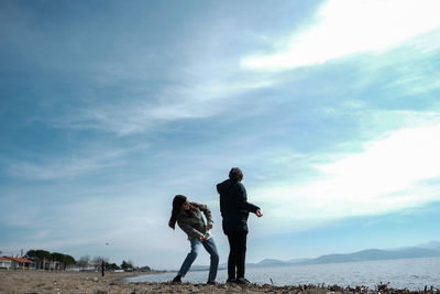 Rear view of youth standing against sky