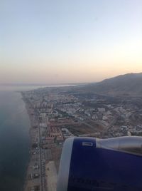 Cropped image of airplane engine over city against clear sky