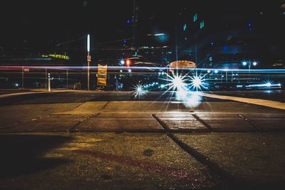 Light trails on illuminated city against sky at night