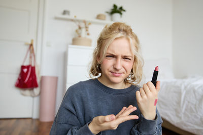 Portrait of smiling young woman using mobile phone at home