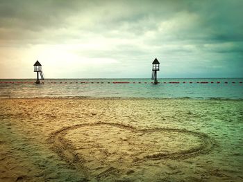 View of calm beach against cloudy sky