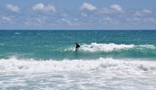 Man surfing in sea against sky