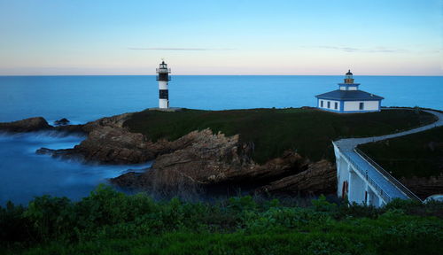 Lighthouse by sea against clear sky