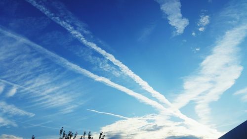 Low angle view of vapor trails against blue sky