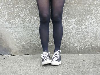 Low section of woman standing against wall