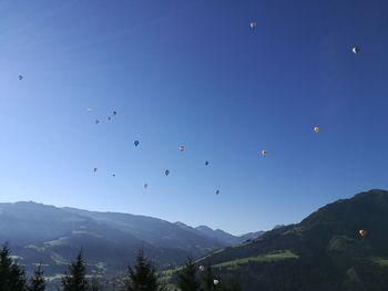 Low angle view of hot air balloons against clear blue sky