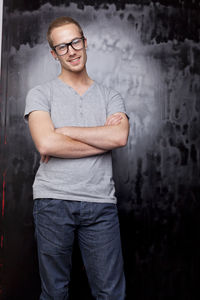 Portrait of young man standing against wall