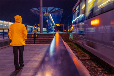 Rear view of person on railroad station platform at night