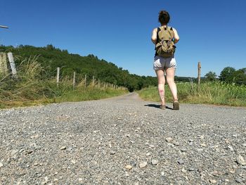 Rear view of woman walking on road