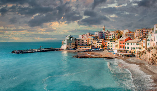 Buildings by sea against sky