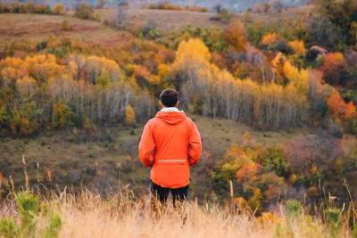 Rear view of man standing on field during autumn