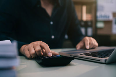 Midsection of man using laptop on table