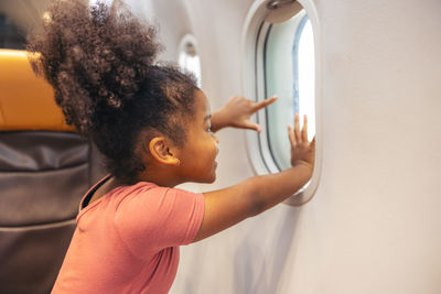 Girls peering out the plane's window. during a holiday flight, a child looks out the window, joyful.